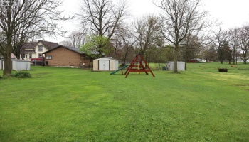 Large backyard with swingset and storage shed