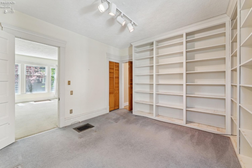 Library/Den/Guest/Hobby room with hallway access to half bath downstairs. Built-in floor to ceiling bookshelves. Hardwood floor underneath in good shape per owner.