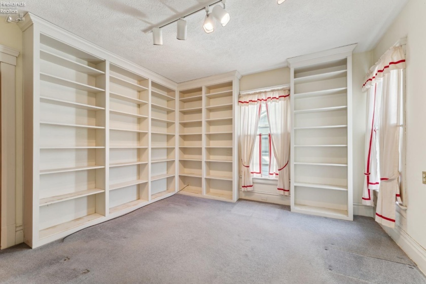 Library/Den/Guest/Hobby room with hallway access to half bath downstairs. Built-in floor to ceiling bookshelves. Hardwood floor underneath in good shape per owner.