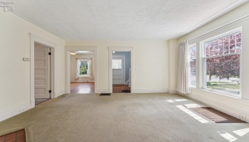 Central living room with expansive south-facing windows and fireplace. Hardwood floor underneath in good shape per owner.