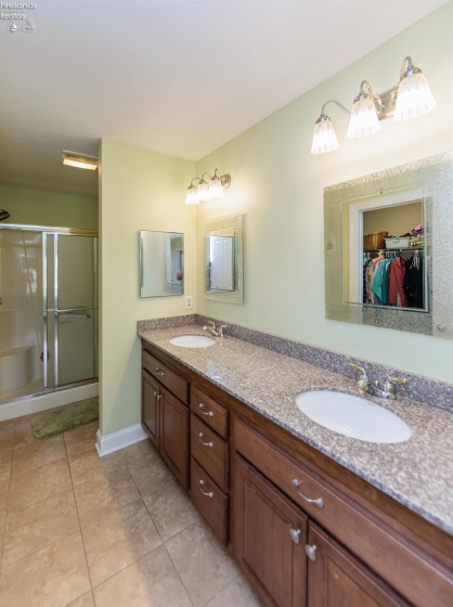 master bathroom with double sinks, tile floor, granite counters, shower and walk-in closet